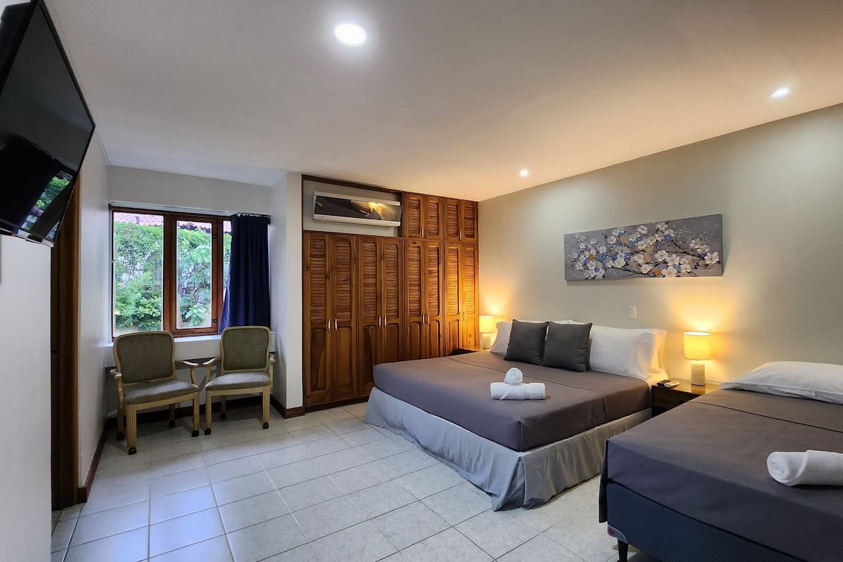 A hotel room with a bed, a desk, a chair, a wardrobe, and a TV.