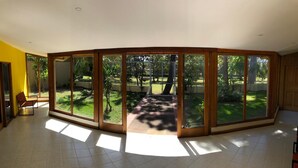 A spacious room with large sliding glass doors leading to a garden. - La Casa de Cariari Al Golf (La Asunción)