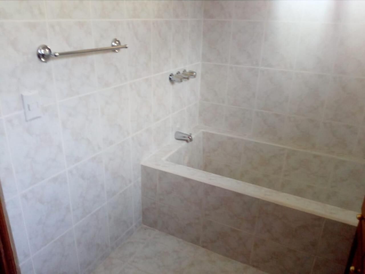 A bathroom with a bathtub, a towel rack, and a showerhead.