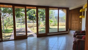 A spacious room with large sliding glass doors leading to a fenced outdoor area. - La Casa de Cariari Al Golf (La Asunción)