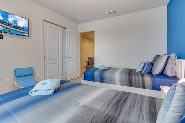 Una habitación de hotel con dos camas, televisión, una silla y una puerta que da a otra habitación.