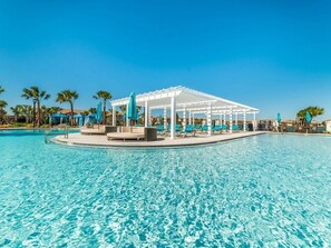 Un área de piscina con una zona de estar cubierta y sillas de descanso.