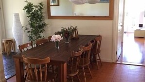 Un comedor con una mesa y sillas de madera, una lámpara colgante y un espejo en la pared.