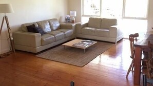 Una sala de estar con dos sofás, una mesa de centro, una lámpara y una mesa de comedor con sillas.