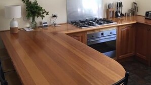 Una cocina con encimera de madera, campana extractora de acero inoxidable, estufa a gas, horno y armarios de madera.