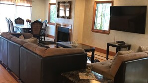 A spacious living room with a large sectional sofa, a fireplace, a flat-screen TV, and a dining area with a table and chairs. - Luxurious 3 BD in Culver City with Pool& Hot Spa (Culver City)