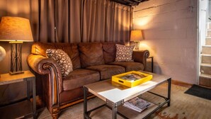 A cozy living room with a brown leather sofa, a wooden coffee table, and a yellow tray. - Secluded, Fenced Cottage, Hot Tub, Fire Pit, Dog Friendly, Nat’l Park (Miller Beach)