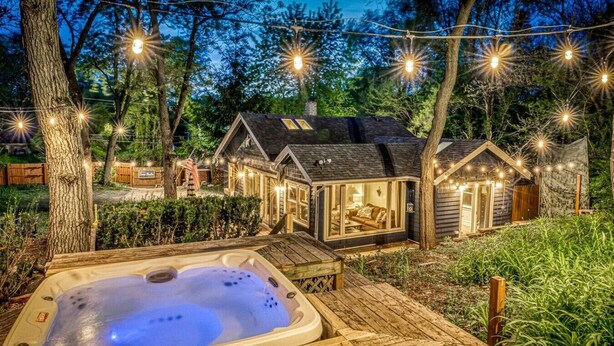 A cozy outdoor hot tub area with a wooden deck, surrounded by a wooden fence and trees. - Secluded, Fenced Cottage, Hot Tub, Fire Pit, Dog Friendly, Nat’l Park (Miller Beach)