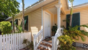 A two-story house with a white picket fence, a front porch with wooden steps, and a door.