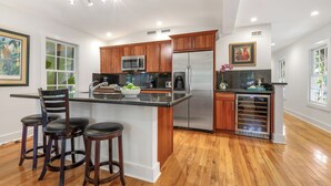 A modern kitchen with wooden cabinets, stainless steel appliances, and a central island with bar stools.