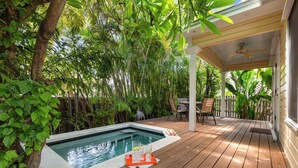 A wooden deck with a hot tub surrounded by lush greenery.
