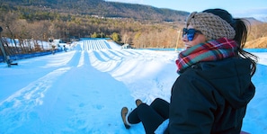 A person sitting on a snow-covered slope with a ski lift in the background.