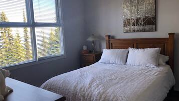 A bedroom with a bed, a nightstand, a lamp, and a window with blinds.