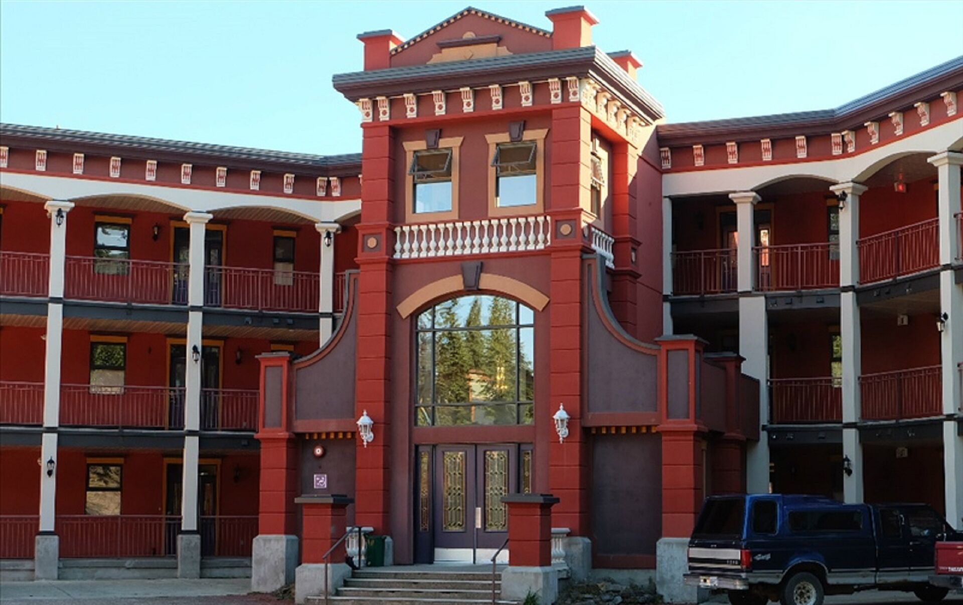 Um edifício de vários andares com uma entrada central destacada por um arco decorativo e portas duplas.