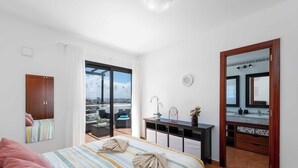 A hotel room with a bed, a desk, a mirror, and a view of the city.