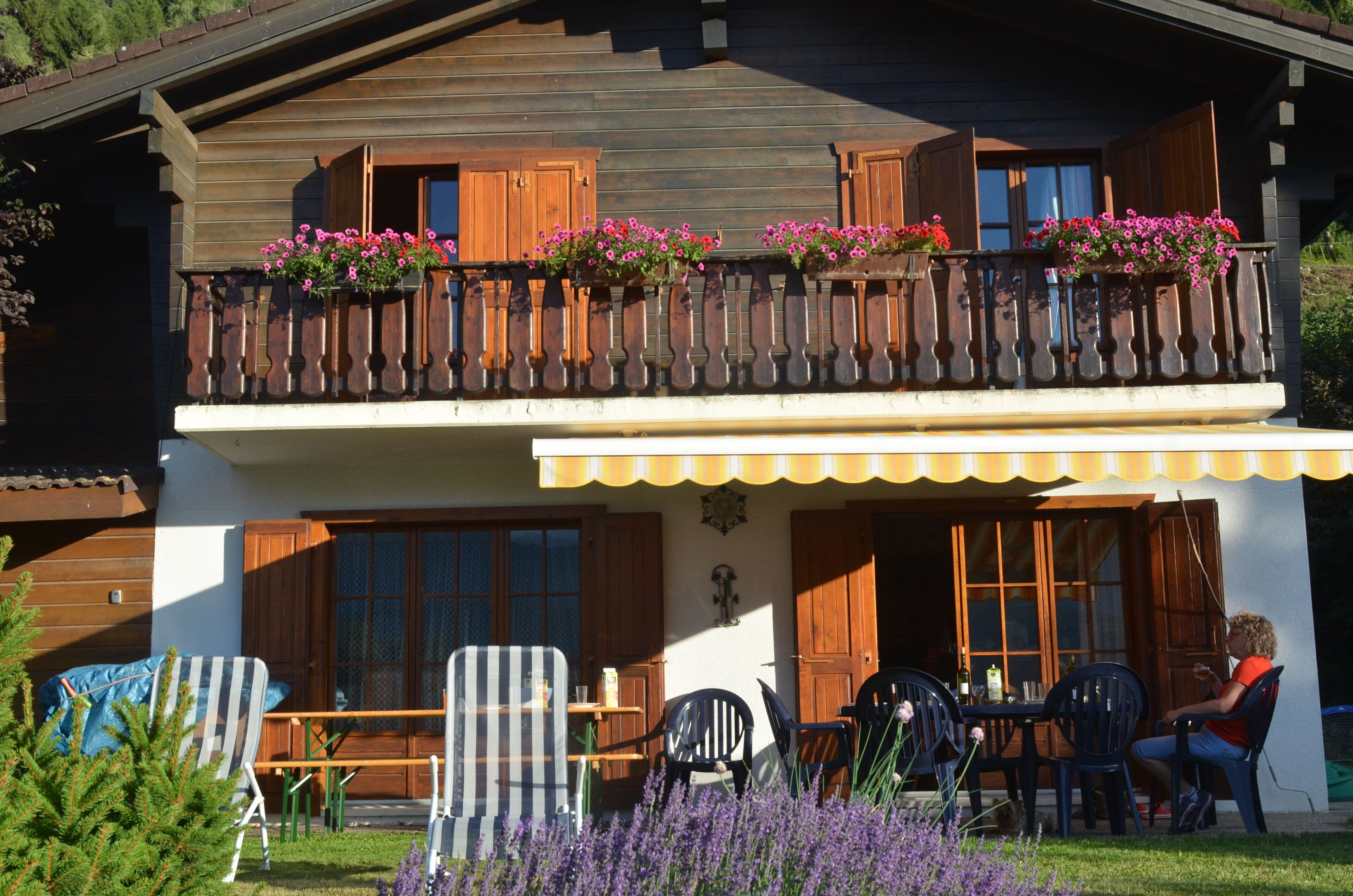 Eine Holzhütte mit Balkon, Sitzgelegenheit im Freien und einem Garten.