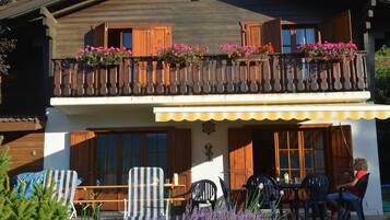Eine Holzhütte mit Balkon, Sitzgelegenheit im Freien und einem Garten.