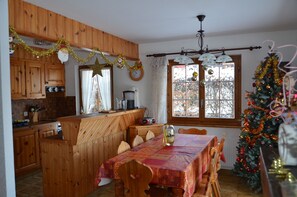Uma cozinha acolhedora com armários de madeira, uma mesa de jantar com cadeiras e um pinheiro de Natal.