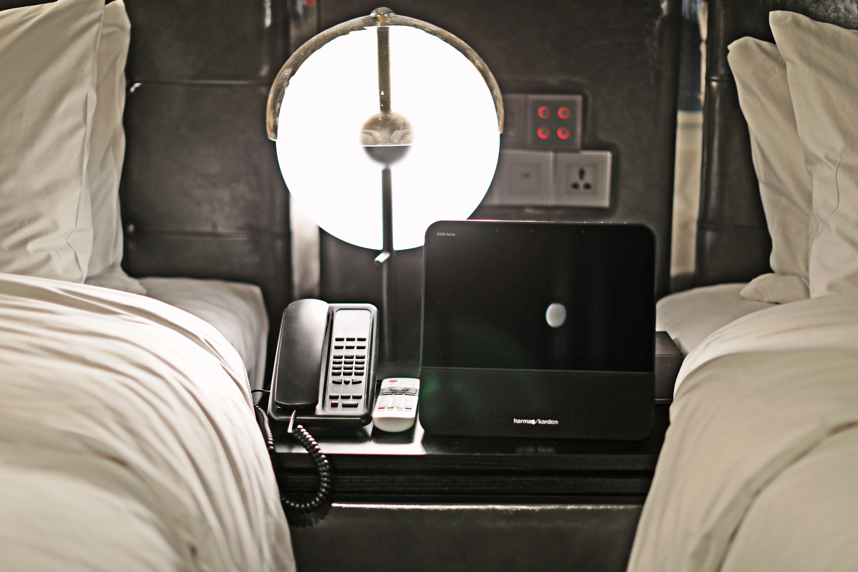 A hotel room with two beds, a desk with a laptop, a telephone, and a lamp.