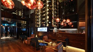 A modern bar area with wooden flooring, seating, and a large bookshelf.