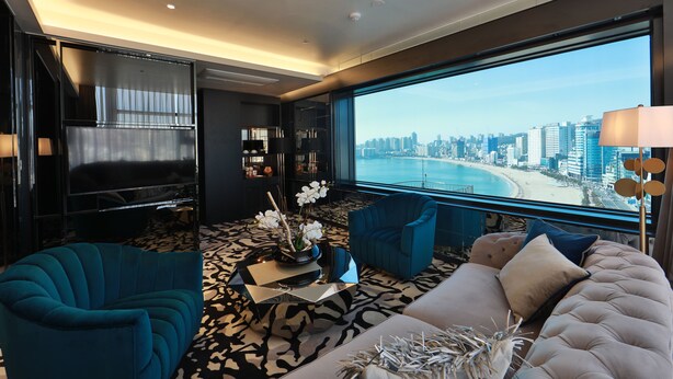 A modern living room with a city view, a large window, and a sofa with decorative pillows.