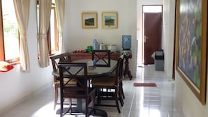 Un coin repas avec une table ronde et des chaises, un distributeur d’eau et un tableau accroché au mur.