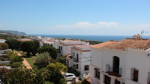 Un quartier résidentiel en bord de mer, avec des bâtiments blancs, un chemin pavé et une vue sur la mer.
