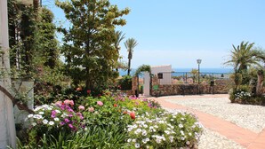Un jardin où s’épanouit une grande variété de fleurs, avec un sentier de pierres qui mène à une porte.