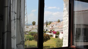 Une fenêtre donnant sur un quartier résidentiel, avec vue sur des maisons et de la verdure.