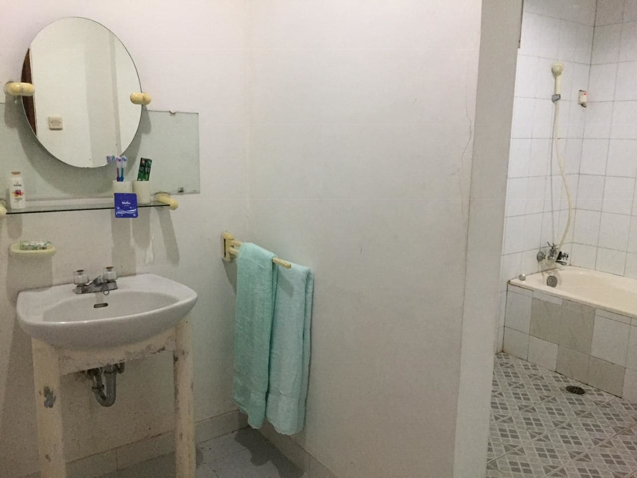 A bathroom with a sink, mirror, towel rack, and a shower area.