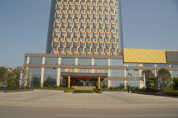 A modern hotel with a large glass facade, a central entrance with a fountain, and a well-maintained outdoor area.