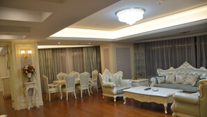 Un salón espacioso con candelabro, un conjunto de sofás y un comedor con sillas y mesa.