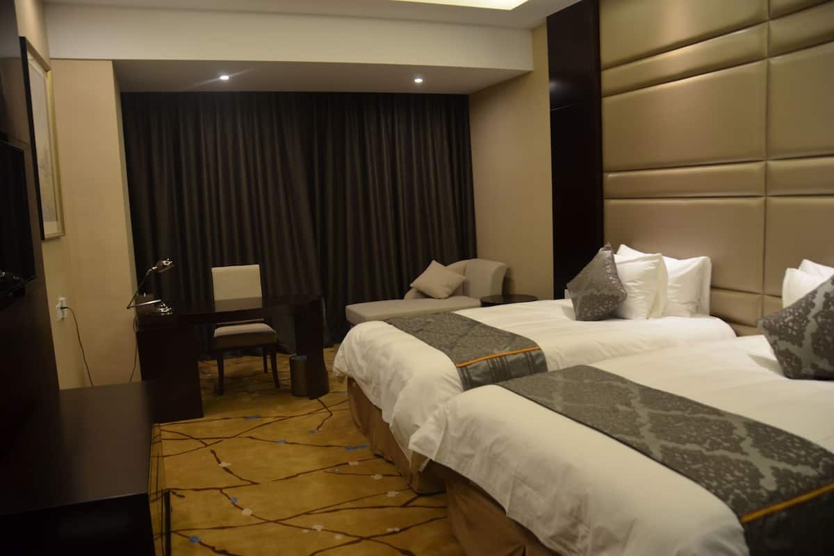 Een hotelkamer met twee bedden, een bureau, een stoel en een televisie.