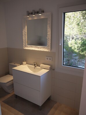Une salle de bain moderne avec un grand lavabo, un miroir et une fenêtre.