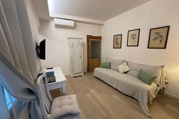 A room with a bed, a desk, a chair, and a window with curtains.