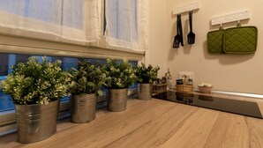 Una cocina con macetas en el alféizar de la ventana, encimera negra y utensilios de cocina colgados en la pared.