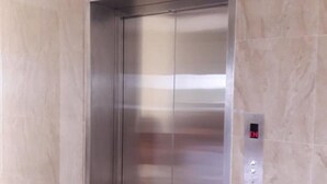 A modern elevator with a metallic finish, a control panel with an 'EN' indicator, and a marble wall. - Godo's Hotel and Restaurant (Culasi)