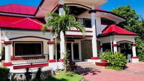 A two-story house with a red roof, white walls, and a stone foundation. - Godo's Hotel and Restaurant (Culasi)
