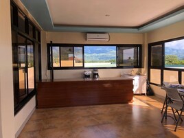 A modern kitchen with a wooden countertop, a sink, and a window overlooking a mountainous landscape.