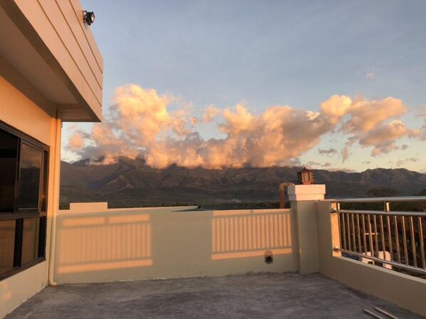 A balcony with a view of mountains and a clear sky.