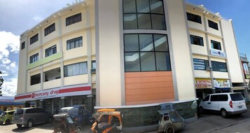 A multi-story building with a pharmacy on the ground floor, a visible sign for 'Mercury Drug'.