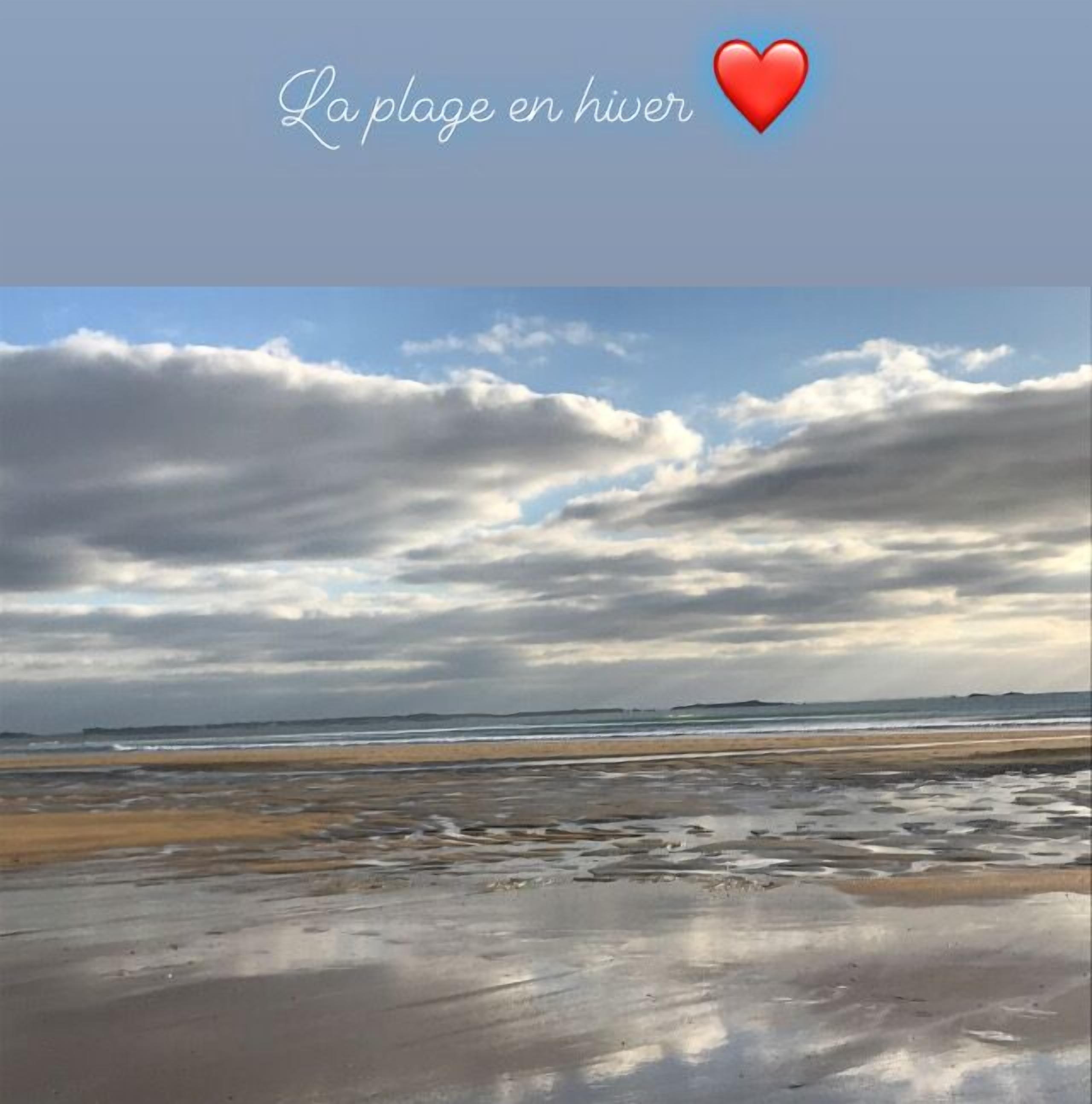 En strand med ett molnigt himlavalv och en våt sandyta.
