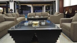 Un salon moderne avec une table basse en verre, des canapés de couleur beige et une vue sur l’extérieur.