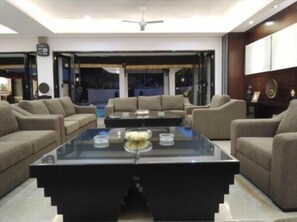 A modern living room with a glass coffee table, beige sofas, and a view of the outside. - Aldeoz Nusa Dua Private Villa Bali (Nusa Dua)