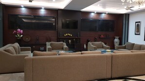 Un salon moderne avec un canapé d’angle, un téléviseur à écran plat, des objets de décoration et un ventilateur de plafond.