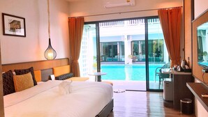 A hotel room with a large bed, a desk, a chair, a small table, a TV, and a view of a swimming pool. - Chaanburi Boutique Resort (Chanthaburi)