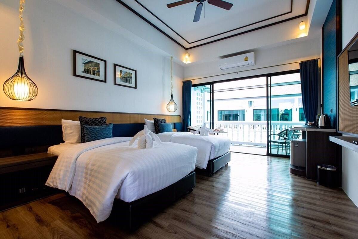 A hotel room with a large bed, a desk, and a balcony with a view.
