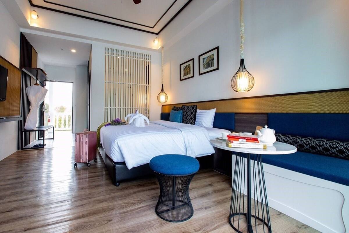 A modern hotel room with a large bed, a seating area with a sofa and a small round table, and a view of the outdoors.