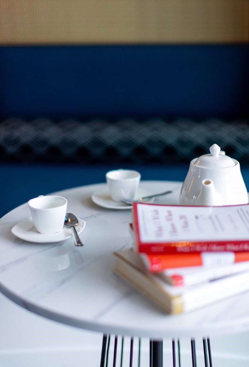 Une table avec une théière blanche, deux tasses blanches, une cuillère et un menu.