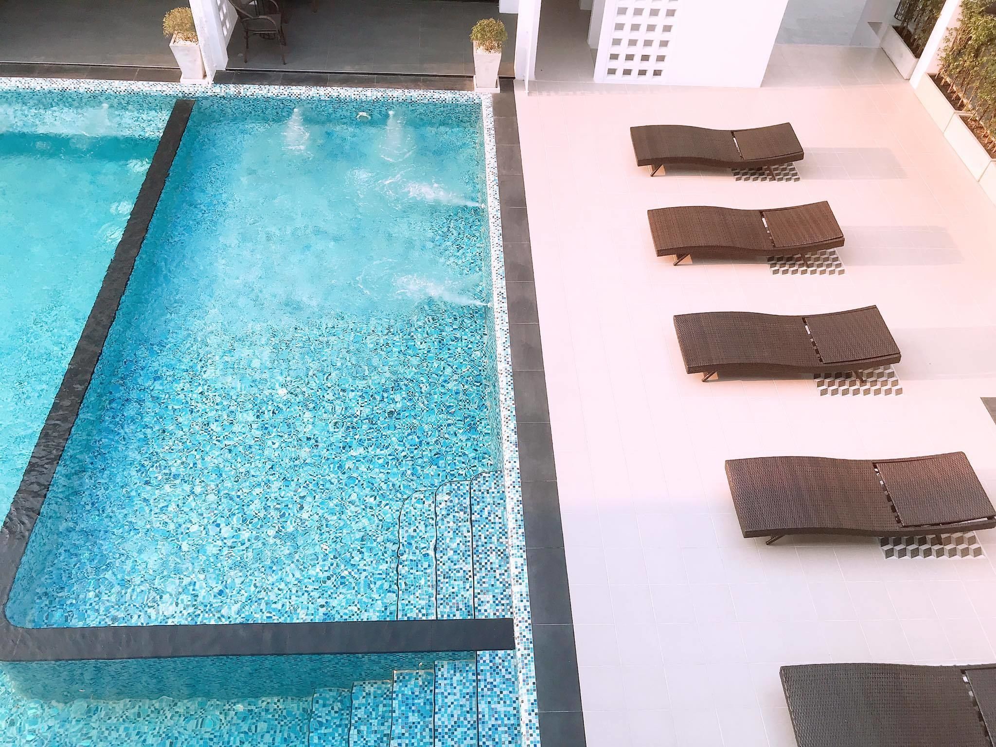Ein Schwimmbecken mit gefliestem Rand und Liegestühlen, die entlang der Seite angeordnet sind.